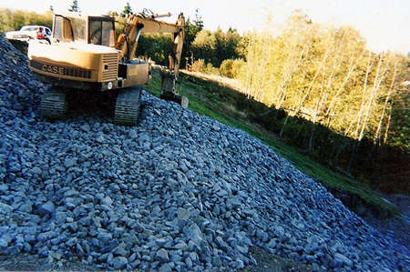 Using heavy equipment to move rock into place to set grade